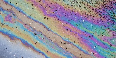 Iridescent surface pattern caused by an oil spill on pavement, illustrating visual cues used in oil spill analysis for rapid identification and characterization.