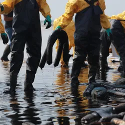 First responders in protective gear clean up an oil spill; future approaches like hydrophobic paper sampling aim to simplify field collection in such conditions.