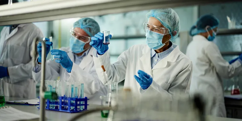 Scientists collaborating in a laboratory setting, using analytical instruments and digital displays, illustrating a team-based approach to biomarker detection.