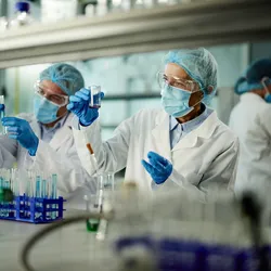 Scientists collaborating in a laboratory setting, using analytical instruments and digital displays, illustrating a team-based approach to biomarker detection.