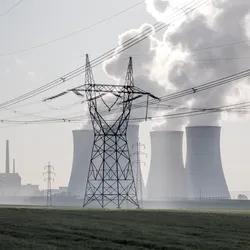Cooling towers and high-voltage power lines at a nuclear power plant, illustrating how radiochemical analysis supports the safe production of electricity from nuclear energy for the power grid.