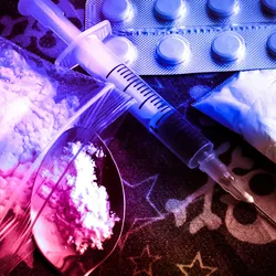  Opioid pills denoting drugs of abuse concept with syringe and preparation spoon.