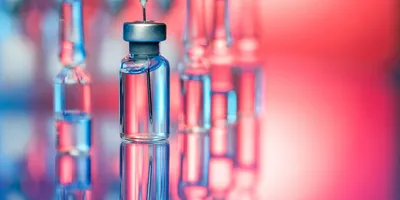 Vaccine vials and a syringe on a clean laboratory surface, representing the final stage of vaccine production and the importance of vaccine quality control.