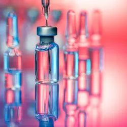 Vaccine vials and a syringe on a clean laboratory surface, representing the final stage of vaccine production and the importance of vaccine quality control.