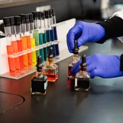 Colorful test tubes arranged in a rainbow pattern representing pigment diversity in laboratory analysis, aligned with ASTM safety standards.