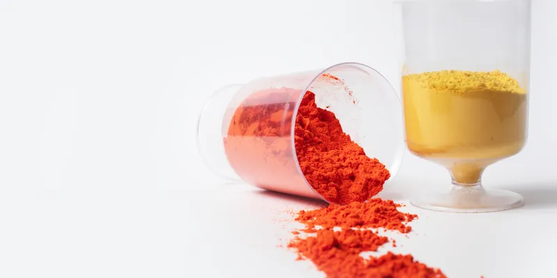 Laboratory-style measuring cups filled with brightly colored powders, visually representing carotenoid pigments used in analytical chemistry for natural pigment identification and quantification
