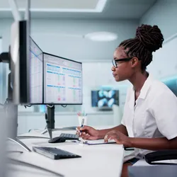 A laboratory professional analyzing complex metabolomics and exposomics data on a desktop computer, using spreadsheets and advanced software tools to review chromatographic results.