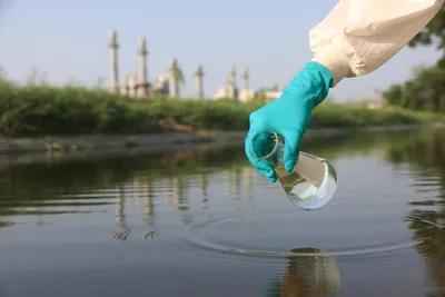 surgical gloved hand holding conical flask to collect water samples