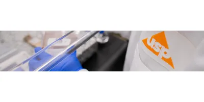 scientist wearing USP-branded lab coat performing analysis