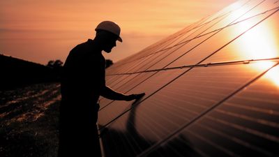 Technical worker in uniform inspecting lab instrumentation as part of renewable energy analysis in a testing environment focused on performance and efficiency.