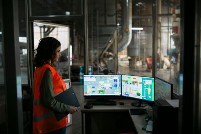 Supervisor controlling an automated production system in a wood factory, representing oversight and precision in pyrolysis gas chromatography, biomass testing, and trace metal analysis workflows.