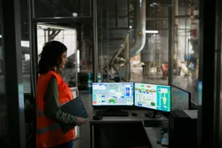 Supervisor controlling an automated production system in a wood factory, representing oversight and precision in pyrolysis gas chromatography, biomass testing, and trace metal analysis workflows.
