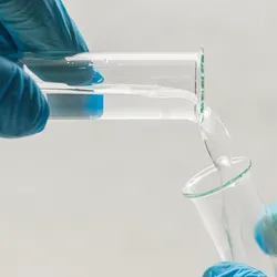 Lab technician pouring water sample into beaker for EPA Method 1633 PFAS testing analysis