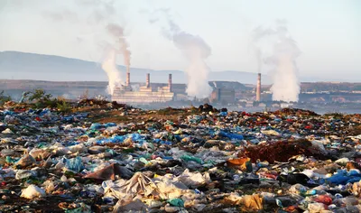 Smoke stacks in background showing pollution over a landfill site.