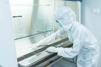 Person cleaning a cleanroom surface to maintain certification standards