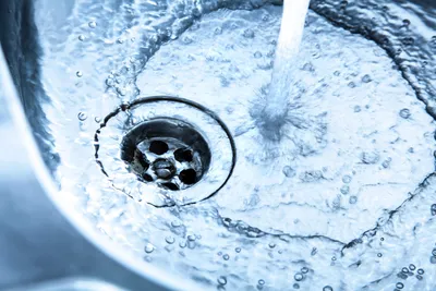 Drain with swirling water, emphasizing the need for broader PFAS approaches.