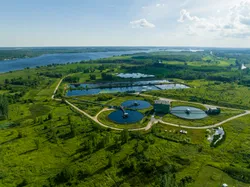 Aerial view of a wastewater treatment plant surrounded by green landscapes.