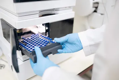 Laboratory technician loading sample vial tray for mass spectrometry.