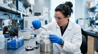 A researcher lowers a tissue specimen into liquid nitrogen with cold vapour spilling over, a stopwatch on the bench beside them.