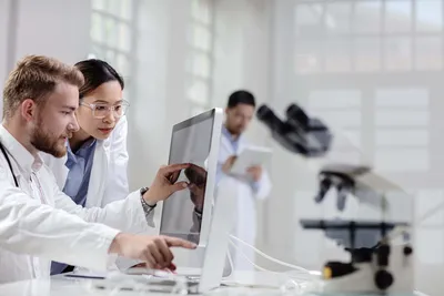 Researchers discussing chromatographic purity results on a computer