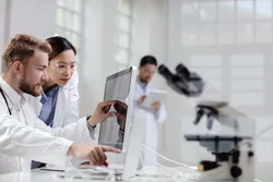 Researchers discussing chromatographic purity results on a computer