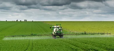 Tractor spraying crop field with pesticides