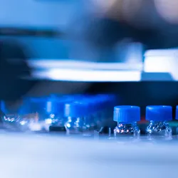 HPLC glass vials with blue caps in the auto sampler. Chemical analysis of plants and human samples